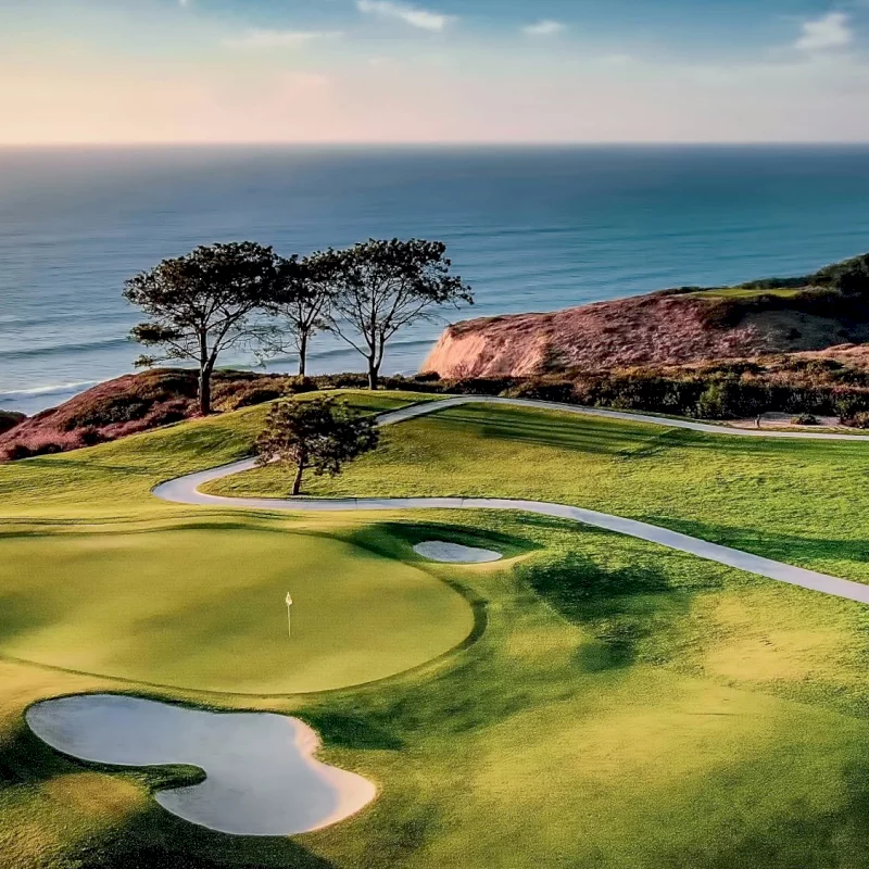 A lush golf course overlooks the ocean near luxury hotels in la jolla during a beautiful sunset.