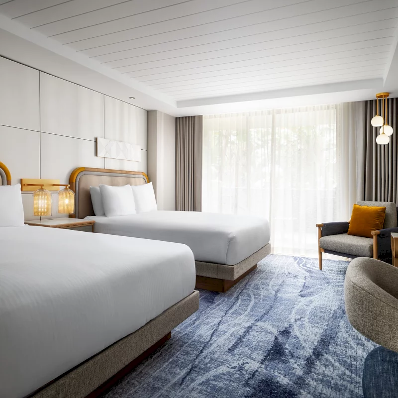 Two queen beds with white linens in a modern room at our luxury boutique hotel in La Jolla.