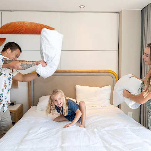 A family enjoys a playful pillow fight in one of the best La Jolla hotels.