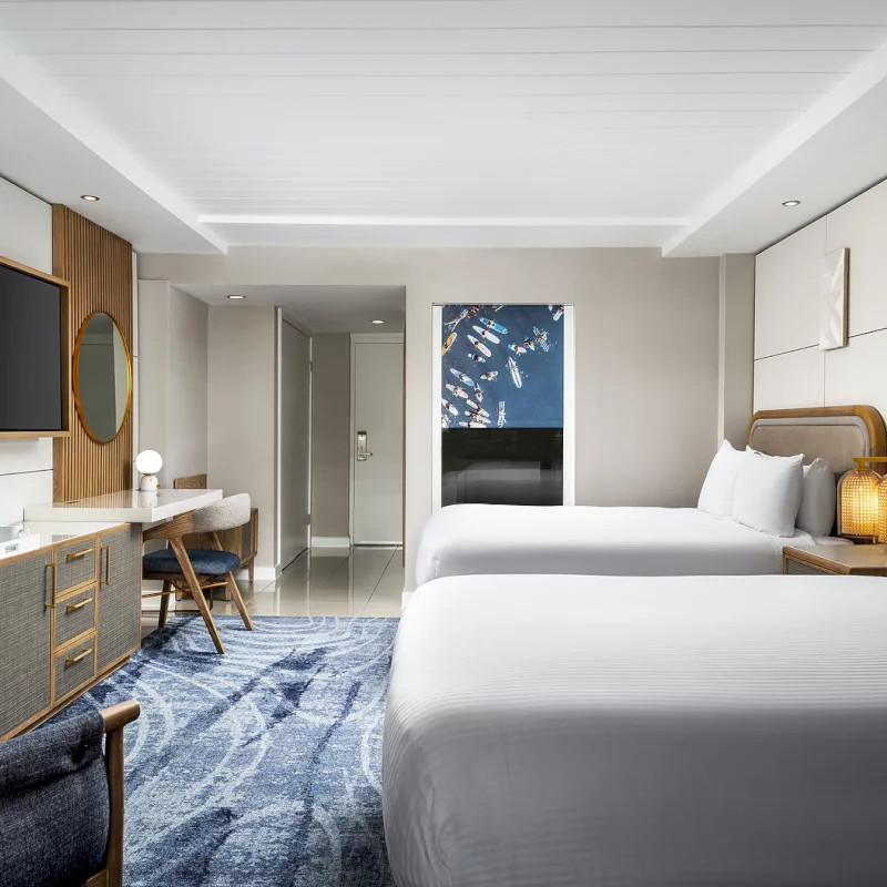 This guest room at our La Jolla boutique hotel features two queen beds and a stylish blue rug.