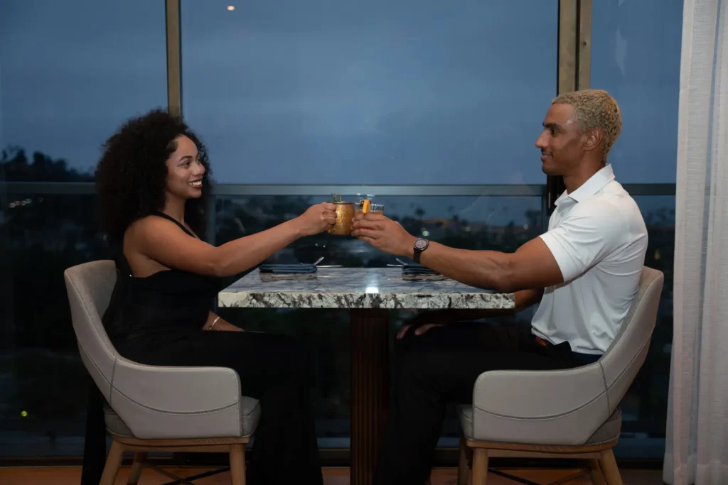 A couple toasts with cocktails at one of the top la jolla restaurants with ocean view.