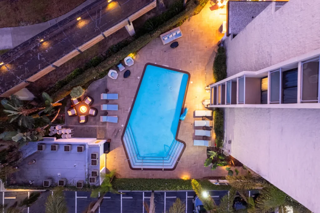 An overhead view of the glowing outdoor pool and fire pit at a luxury hotel in La Jolla.